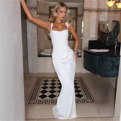 Woman in a white dress standing in a bathroom with marble walls and a checkered floor.