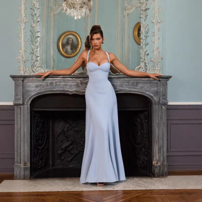 Woman in a light blue evening gown standing in an elegant room with a fireplace and decorative mirrors. Main image